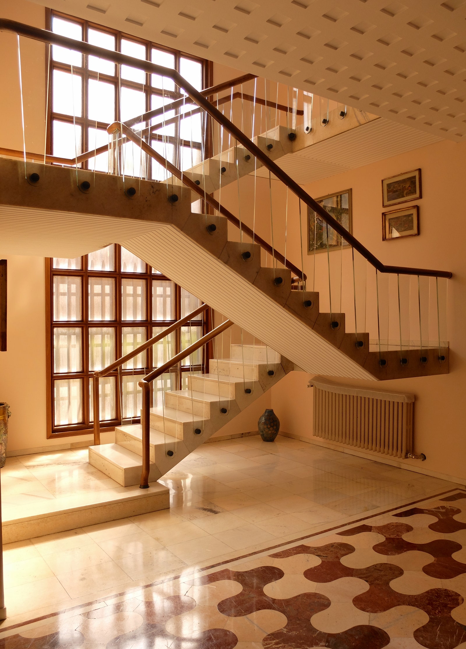 The central staircase with its walnut bannisters and Murano glass balustrade panels rises airily from the villas...