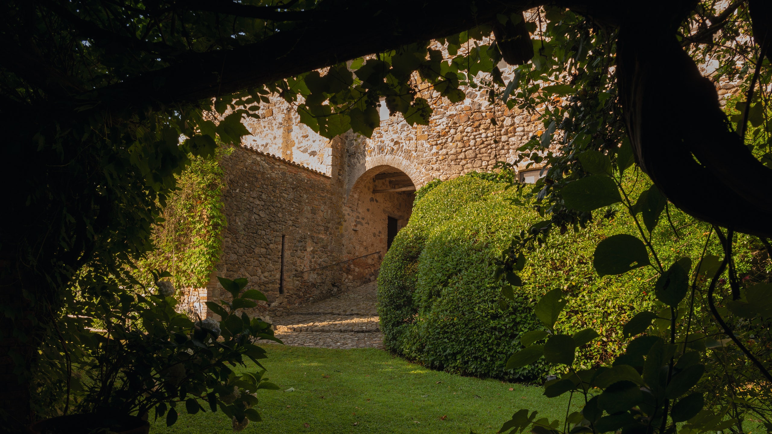 A view of the garden at La Torricella and an archway large enough for carriages to pass through